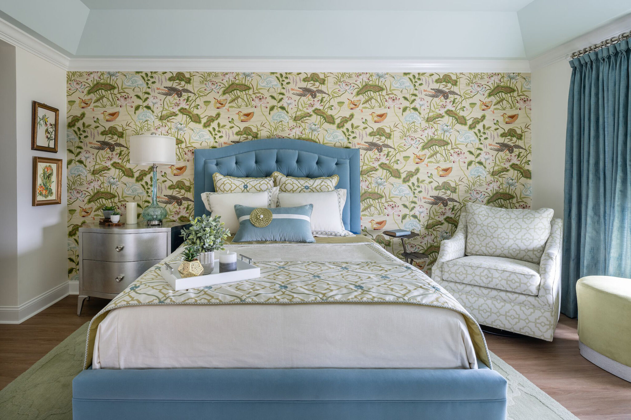 Bedroom with floral accent wallpaper, a blue bed frame, and matching blue drapes