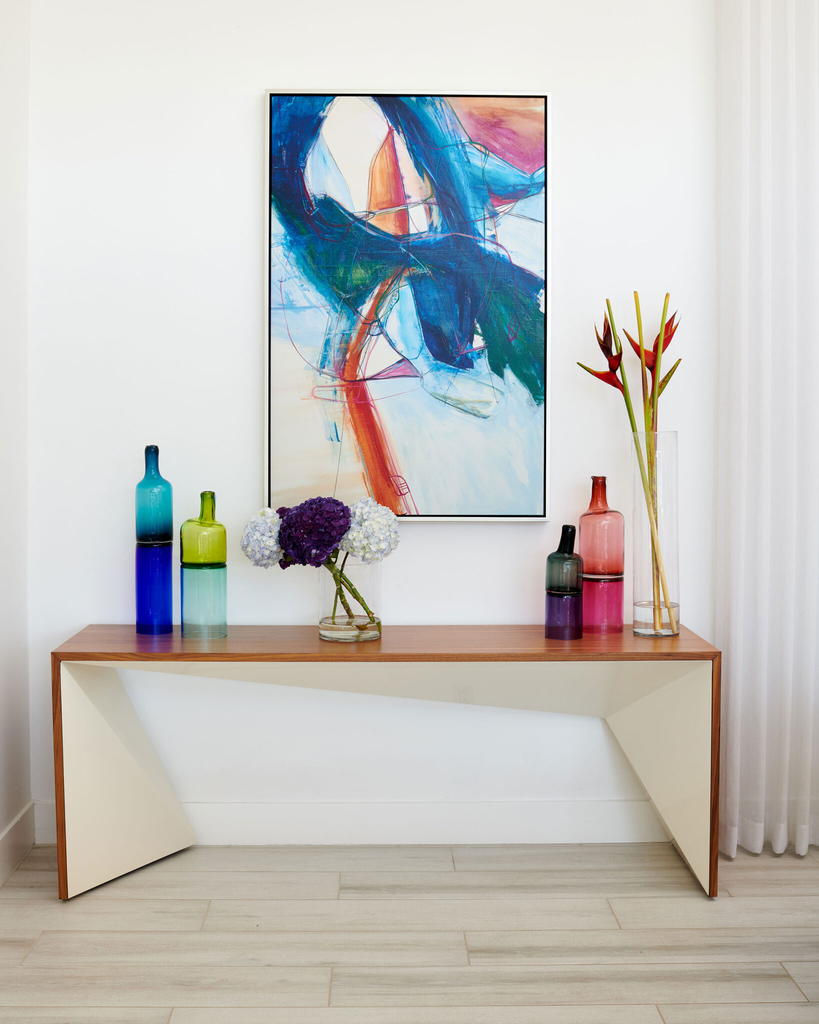 Console table with colorful glass art and an abstract painting on the wall