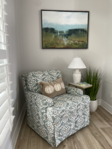 Patterned accent chair in a corner with artwork on the wall above